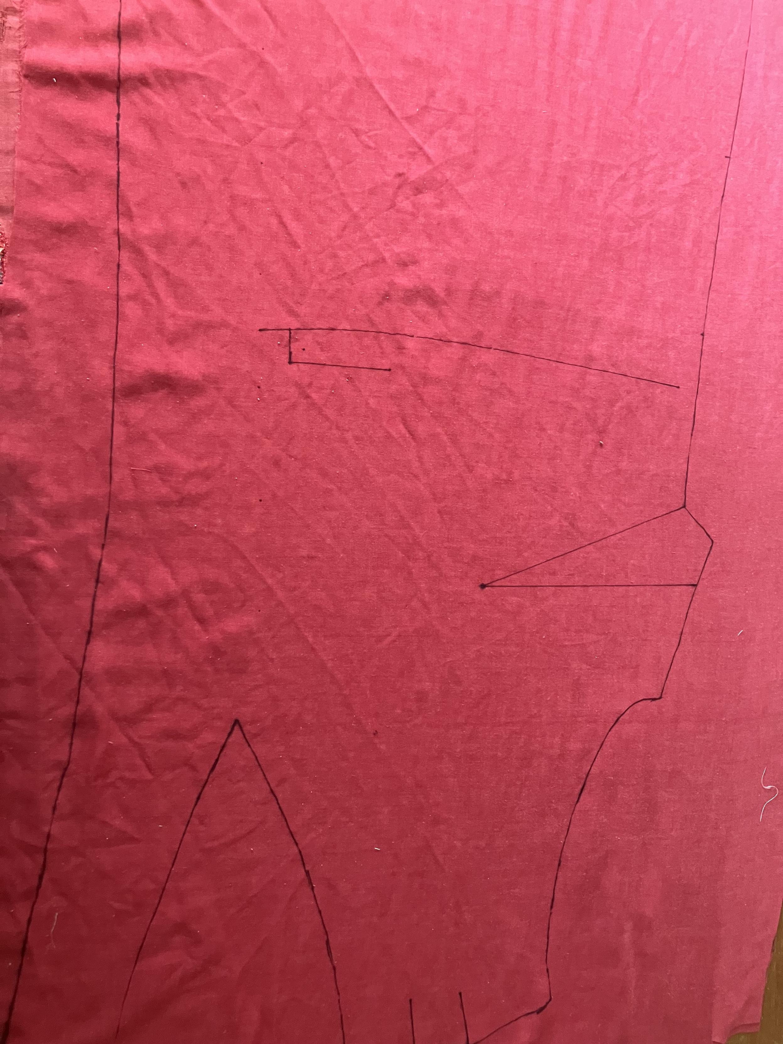 The top part of a dress marked out in black pen on a red sheet